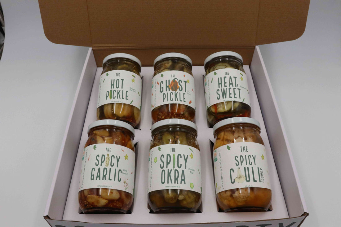 Pickle Party box holding six jars: The Hot Pickle, The Ghost Pickle, The Heat Sweet, Spicy Garlic, Spicy Okra and Spicy Cauli