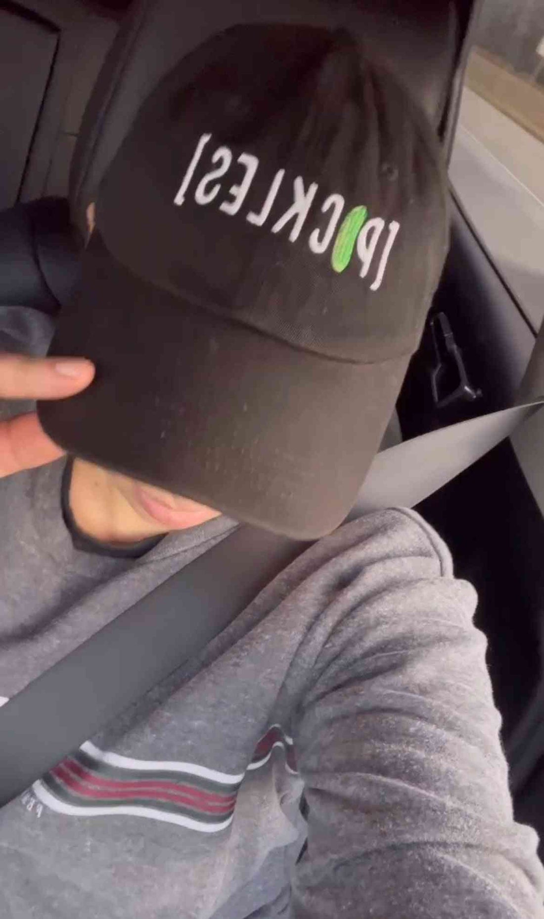 Black Pickle Cap Hat with embroidered logo, stylish headwear for food gift baskets, worn by person in vehicle, side profile