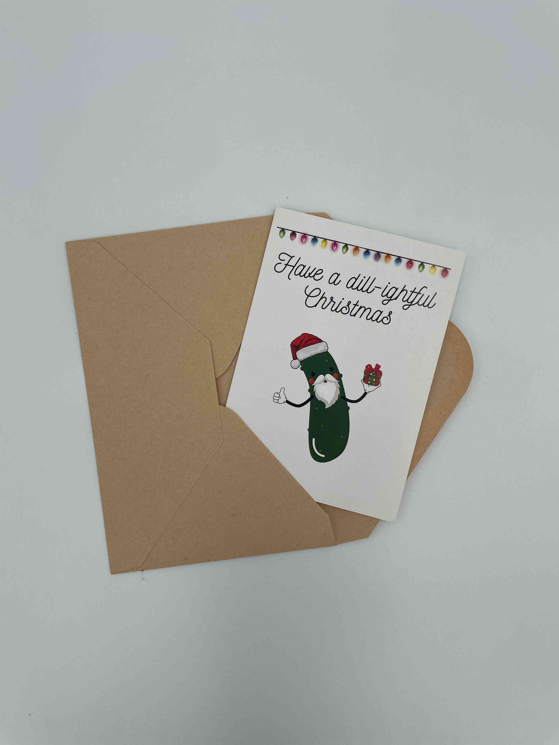 Have a Dill-ightful Christmas card with a bearded Santa pickle, on a kraft envelope