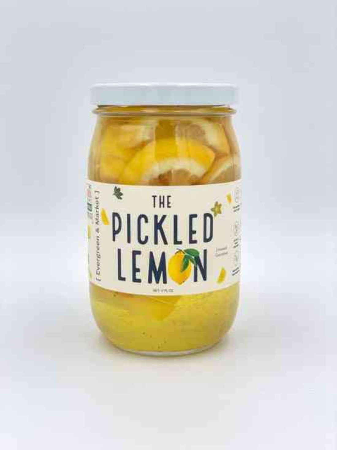 Glass jar of pickled lemons with lemon slices and peels in a tangy yellow brine, labeled 'The Pickled Lemon' for cocktails and salads.
